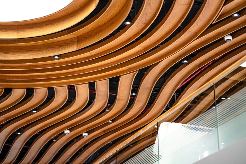 Curved wooden ceiling design with glass railing in a modern Dubai interior.